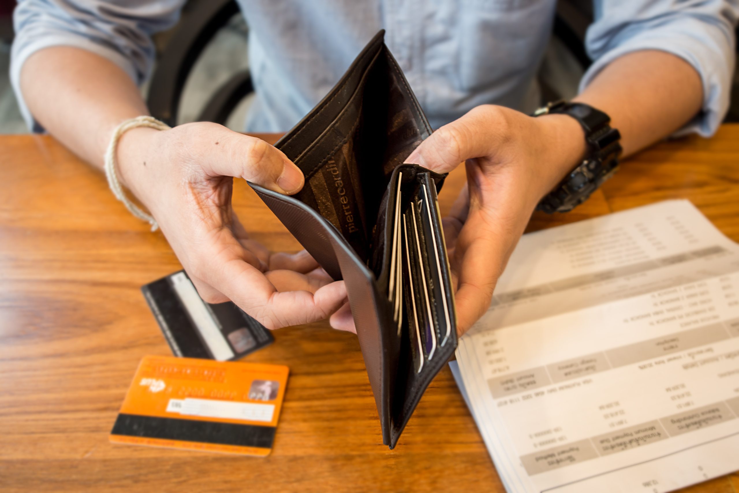 Customer holding an open wallet and bank card while reviewing finance paperwork for a vehicle purchase